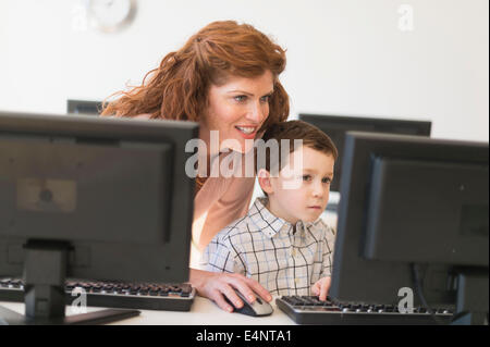 Boy (6-7) and teacher using computer Stock Photo