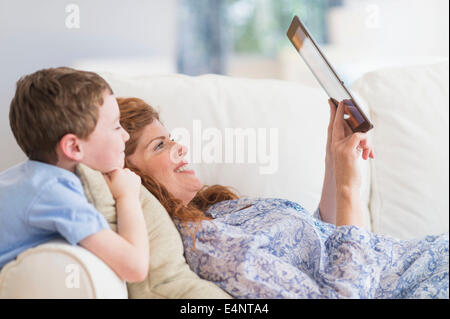 Mother and son (6-7) lying on sofa using digital tablet Stock Photo