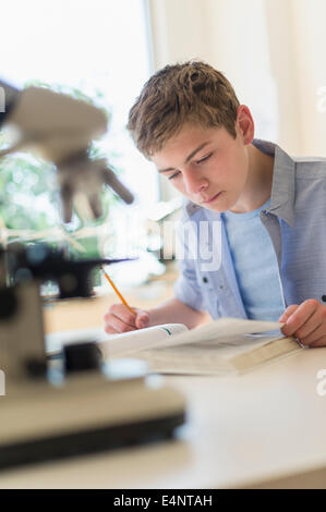 Teenage boy (16-17) reading book in laboratory Stock Photo