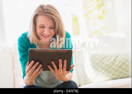 Portrait of woman on sofa using digital tablet Stock Photo