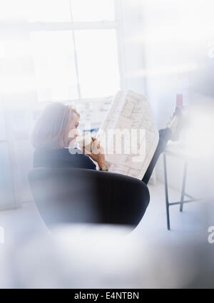 Business woman looking at blueprint in office Stock Photo