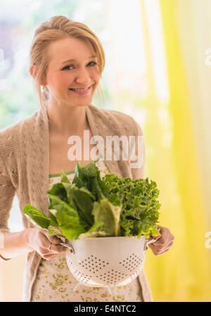 Portrait of young woman holding lettuce in colander Stock Photo