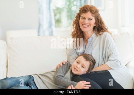 Mother and son (6-7) relaxing on sofa Stock Photo