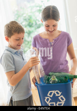 Boy and girl (8-9, 10-11) placing bottles in garbage bin Stock Photo