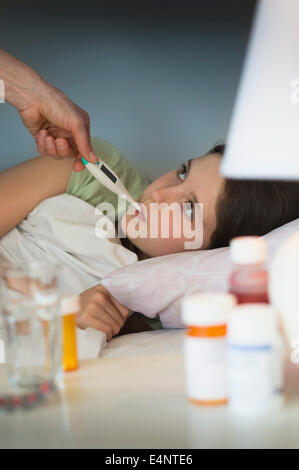 Sick girl (8-9) with thermometer in mouth Stock Photo