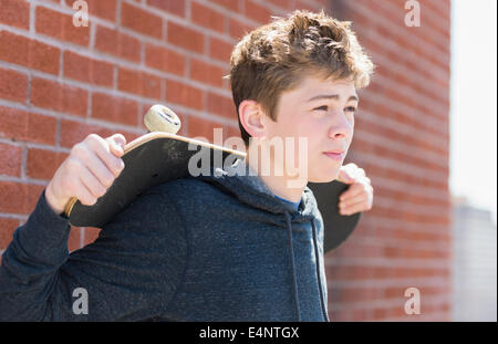 Teenage boy (16-17) holding skateboard Stock Photo