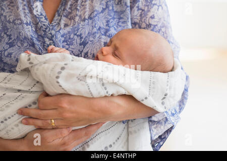Close up of baby boy (2-5 months) sleeping in mother's arms Stock Photo