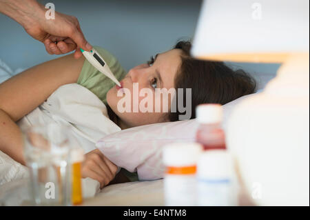 Sick girl (8-9) with thermometer in mouth Stock Photo