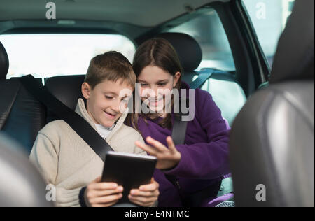 Boy and girl (8-9, 10-11) using digital tablet in car Stock Photo