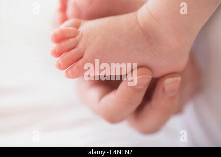 Close up of mother's hand touching baby boy's (2-5 months) foot Stock Photo