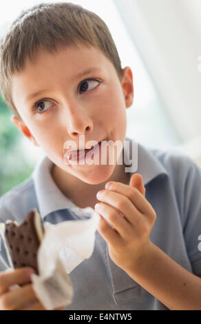 Boy (8-9) eating ice cream sandwich Stock Photo