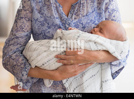 Close up of baby boy (2-5 months) sleeping in mother's arms Stock Photo