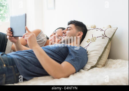 Young couple using digital tablet in bed Stock Photo
