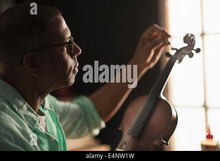 Mature man fixing violin in his workshop Stock Photo