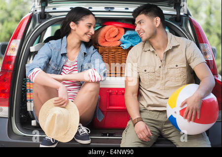 Young couple sitting in open car trunk Stock Photo