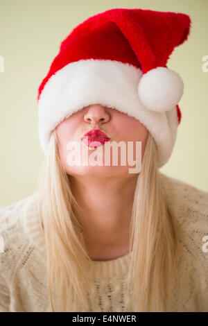 Studio Shot of woman wearing santa hat and puckering Stock Photo