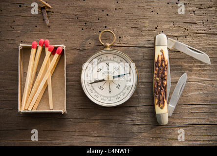 Studio Shot of matchsticks, compass and knife on wooden board Stock Photo