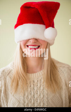 Studio Shot of woman wearing santa hat smiling Stock Photo