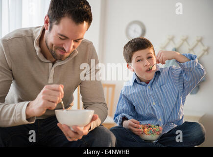 Father and son (8-9) eating breakfast cereal Stock Photo