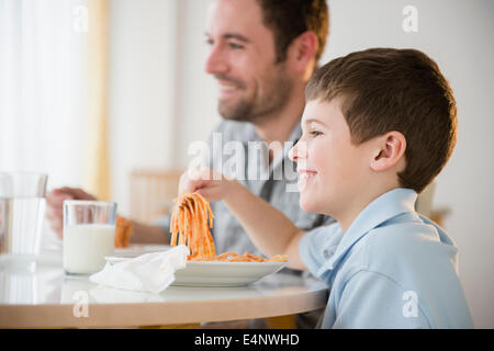 Father and son (8-9) eating spaghetti Stock Photo