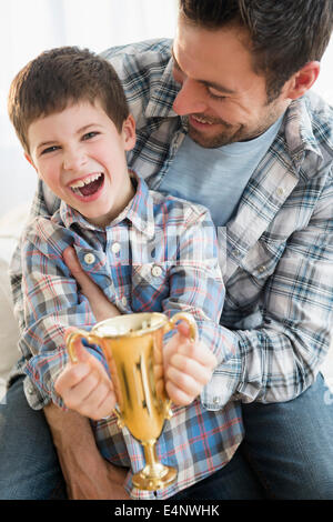 Father and son (8-9) holding trophy Stock Photo