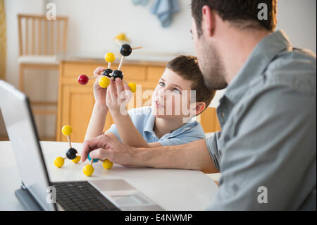 Father and son (8-9) looking at molecule model stack Stock Photo