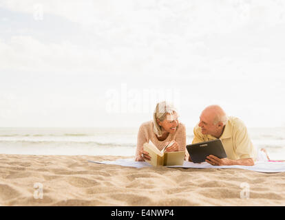 Senior couple reading books on beach Stock Photo