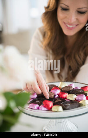 Woman choosing chocolate from cake stand Stock Photo