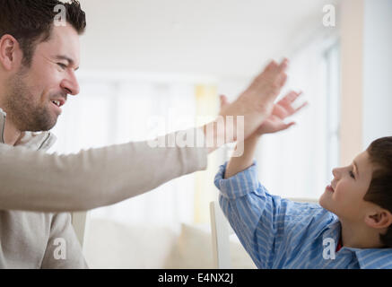 Father and son (8-9) high fiving Stock Photo
