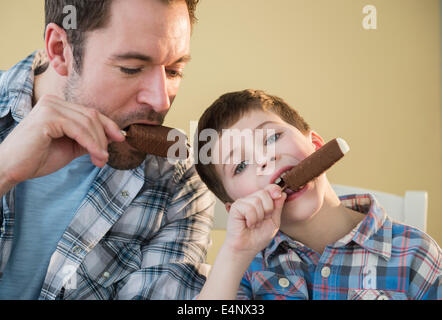 Father and son (8-9) eating ice creams Stock Photo