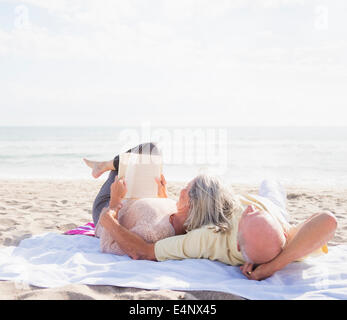 Senior couple reading books on beach Stock Photo