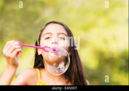 Portrait of girl (8-9) blowing bubbles Stock Photo