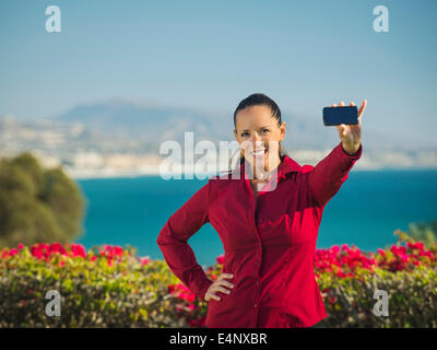 USA, California, Dana Point, Portrait of smiling woman holding smartphone Stock Photo
