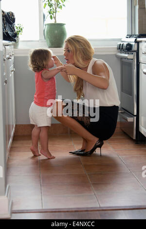 Woman playing with daughter (6-11 months) in kitchen Stock Photo