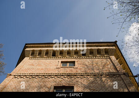 red brick manor architectural fragment with small windows and ornaments on blue sky background Stock Photo