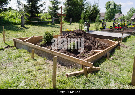 Fresh grave soil and foundation in cemetery. Graveyard landscape. Stock Photo