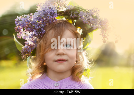 Little summer girl in lilac flowers garland Stock Photo