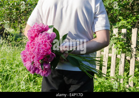 close up of man back with peony flower in hand Stock Photo