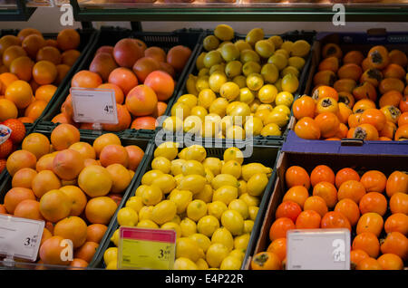 organic fresh orange lemon persimmon fruit pile in plastic boxes in store Stock Photo