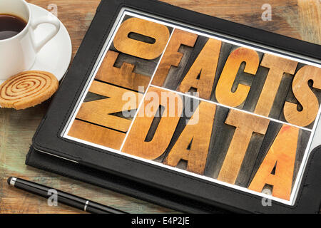 information, data, facts word abstract in vintage letterpress wood type printing blocks on a digital tablet with cup of coffee Stock Photo