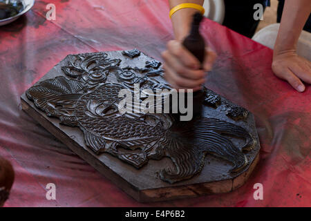 Man demonstrating Chinese woodblock printing at cultural festival - USA Stock Photo