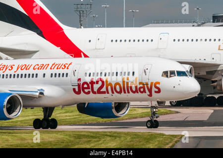 Jet 2.com Boeing 757 aircraft taxies in front of an Emirates Airbus A380 illustrating the size differentials of each aircraft Stock Photo