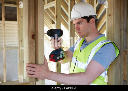 Construction Worker Using Cordless Drill On House Build Stock Photo
