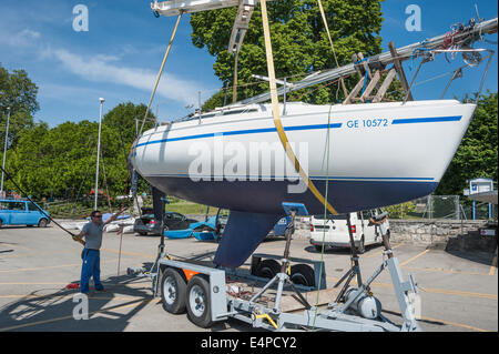 A man raising a yacht from a trailer, with a crane, ready for putting it in the water. Stock Photo