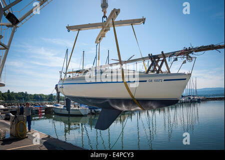 A sailing yacht being lifted into the water with a crane, at a port on Lac Leman (Lake Geneva) Stock Photo