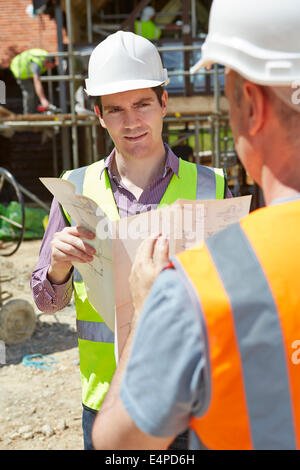 Architect Discussing Plans With Builder On Construction Site Stock Photo