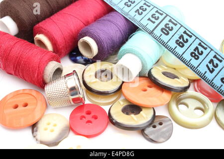 Colorful spools of thread with a tape measure, thimble and buttons isolated on white Stock Photo