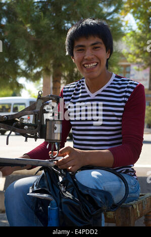 Man working on a sewing machine by the roadside, Shakhrisabz, Shar-e Sabz or Shahrisabz, Uzbekistan Stock Photo