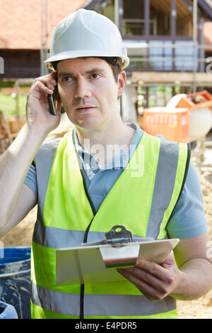 Construction Worker On Building Site Using Mobile Phone Stock Photo