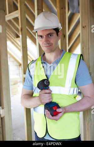 Builder On Construction Site Holding Cordless Drill Stock Photo